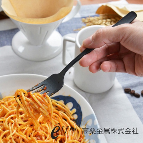 黑色金屬餐叉，用於叉取義大利麵，手持餐叉的背景是白色馬克杯和咖啡濾杯。