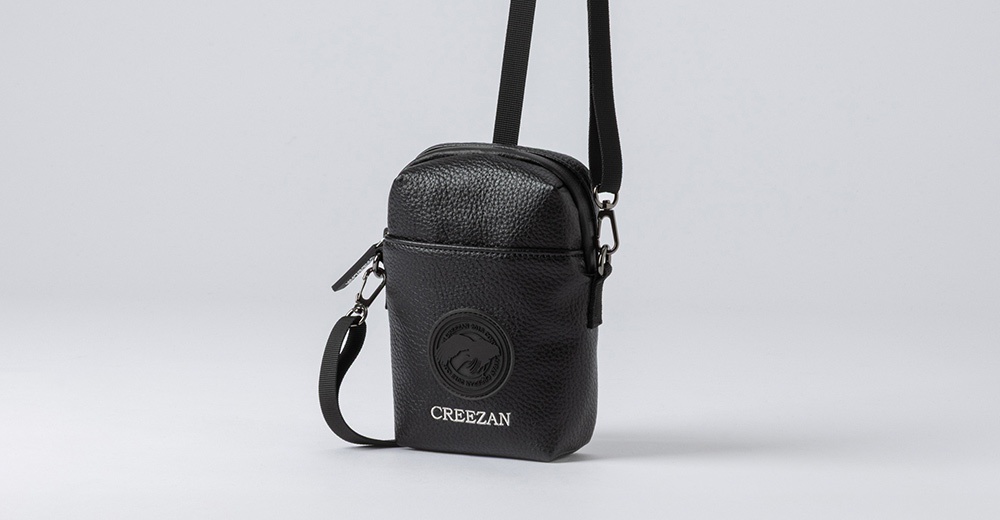 黑色荔枝紋皮革迷你側背收納包，附有可調節斜背帶及品牌Logo壓紋。