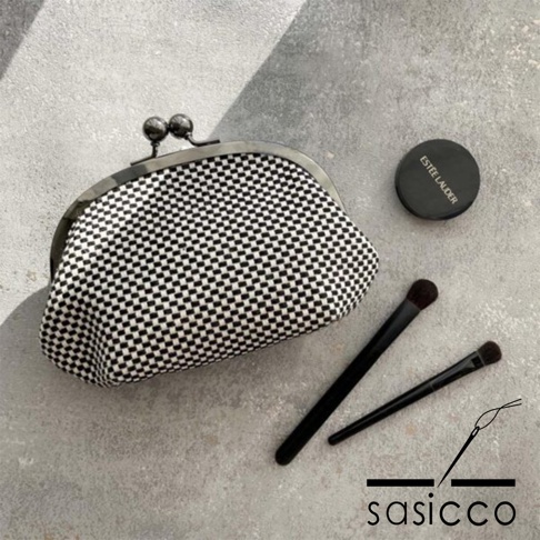 三河木綿刺子織口金零錢包，黑白格紋織紋，搭配銀色雙球口金，旁邊擺放兩支化妝刷及一盒Estee Lauder化妝品。