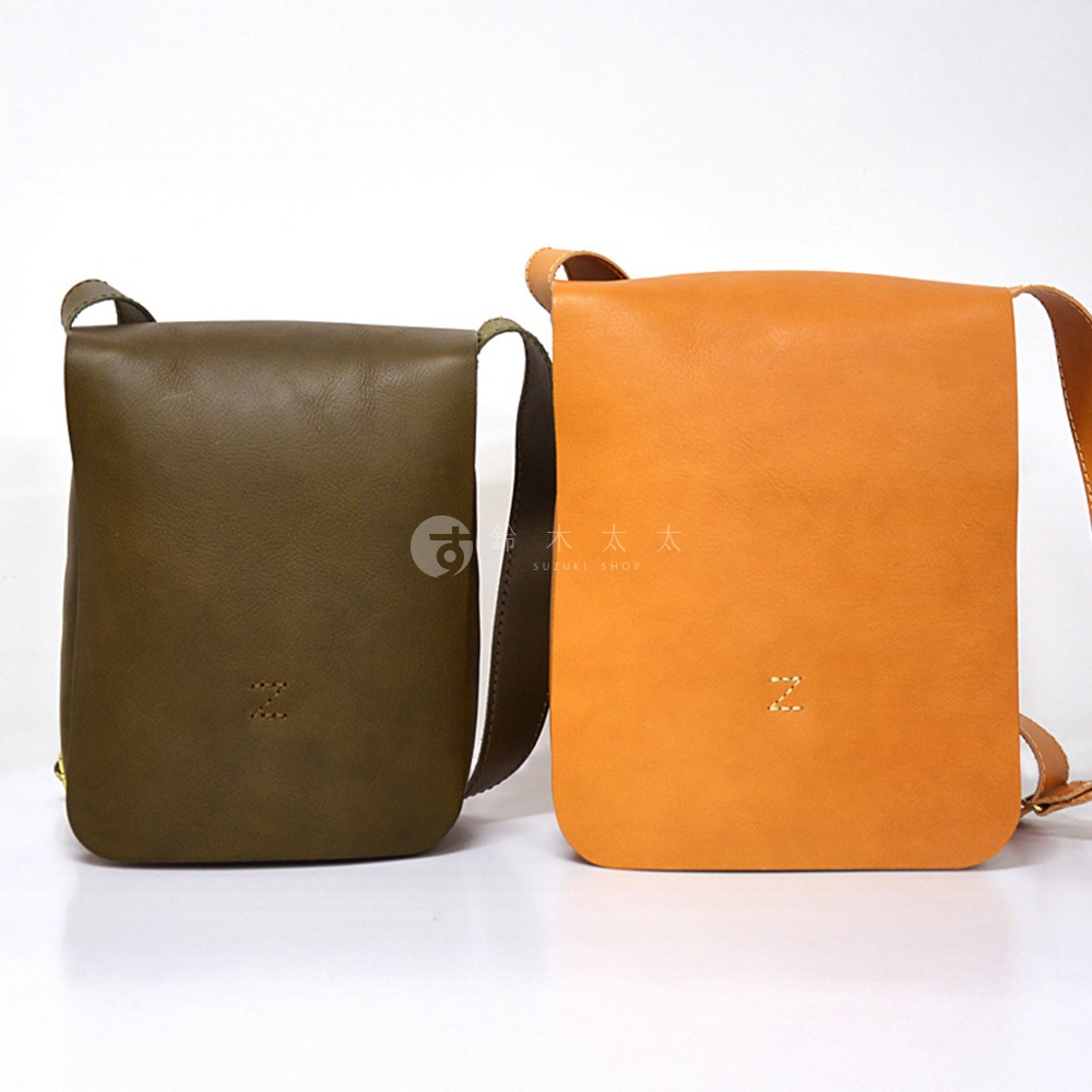 日本製 HERZ 職人手作皮革軟皮直式斜背包，左為墨綠色，右為橘色，皆有品牌縫線識別。
