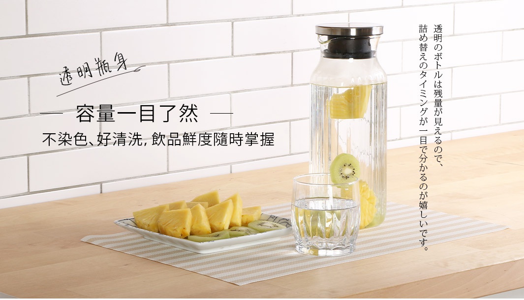 透明耐熱玻璃水壺，附不鏽鋼蓋和把手，壺身有直條紋路，內部裝有水、鳳梨塊和奇異果片。旁邊有一個相同材質的玻璃杯，也裝有水和水果。