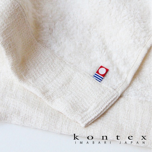 米白色今治厚感兔耳連帽浴巾，材質為柔軟毛圈，一角有紅色方塊標籤，印有白色圓形和藍色條紋。