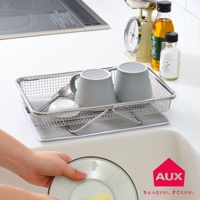 不鏽鋼網格瀝水籃，內有兩個灰色馬克杯、一個白色小碟子和一把湯匙。籃子下方鋪有灰色吸水布。