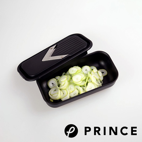 黑色的磨泥切片兩用盒，盒內盛有切片的蔥段，盒蓋上設有V型金屬刀片。