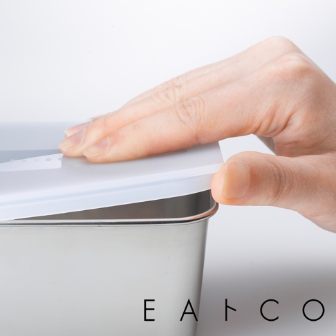 一隻手正在將白色半透明蓋子蓋上一個日製不鏽鋼食物儲存盒。