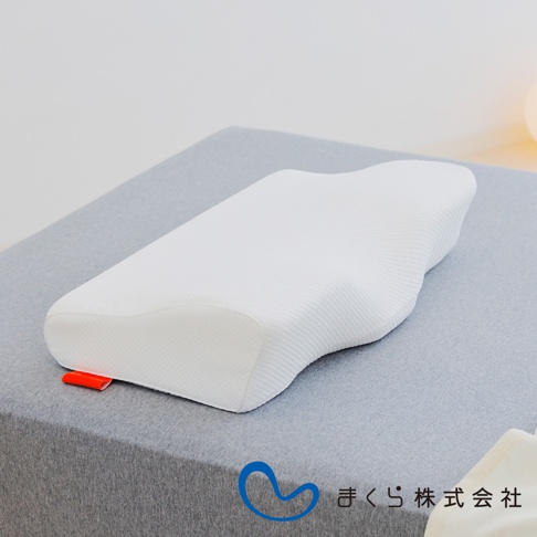 白色護頸止鼾枕，採用記憶棉材質，枕面有網狀紋理，呈現人體工學曲線，一側有紅色織帶。