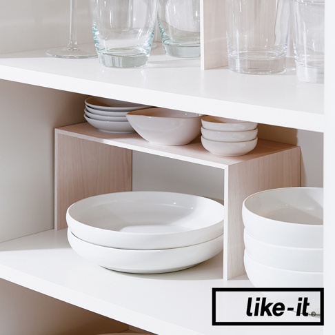 PLUS RACK 多用途雙層木紋整理架，由淺木紋色材質製成，用於收納白色碗盤和玻璃杯。