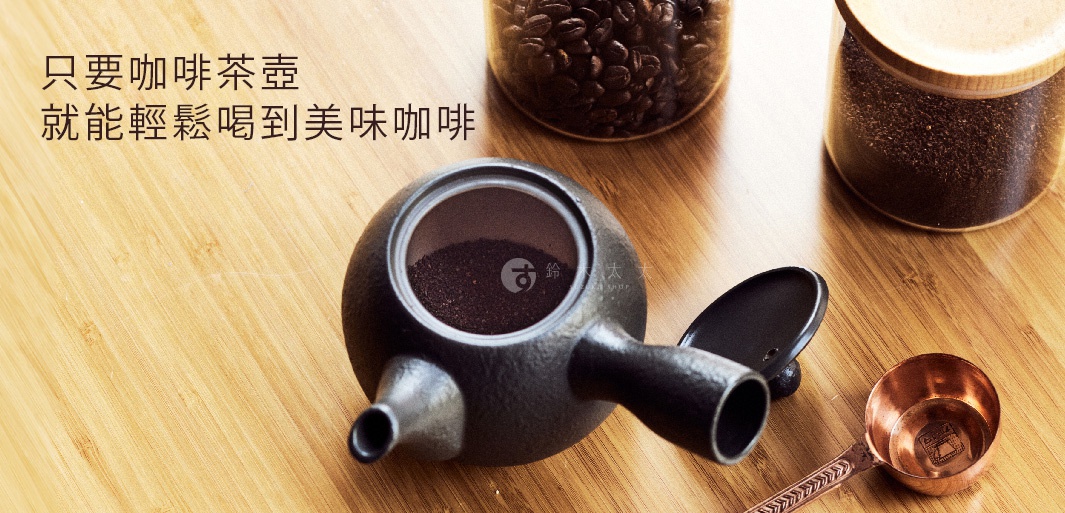 黑色常滑燒咖啡急須茶壺，壺身圓潤，帶有側柄及壺嘴，壺內盛有咖啡粉。旁邊有銅製咖啡量勺和裝有咖啡豆的玻璃罐。