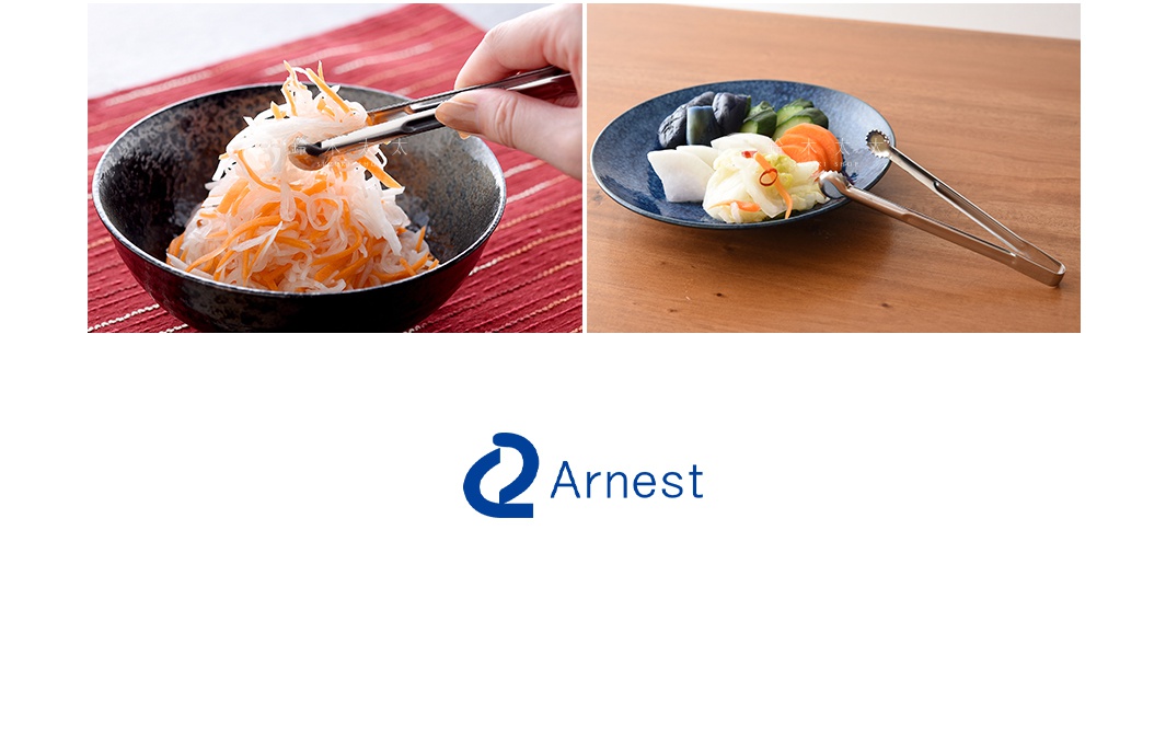 逸品物創不鏽鋼萬用料理夾，銀色，夾取碗中切絲的白蘿蔔與紅蘿蔔，以及盤中醃漬的小黃瓜、茄子、白蘿蔔等漬物。