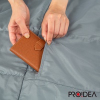 一雙手正將一個棕色皮革錢包塞進灰色兩用睡袋的口袋。