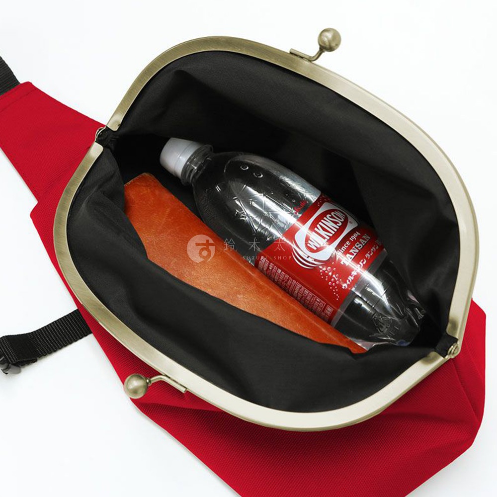 一個裝有威爾金森碳酸飲料瓶和橘色物品的紅色斜背包，打開的樣子。