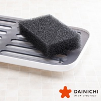 黑色海綿放置於白色帶有灰色網格的瀝水盤上，海綿表面有細密的氣孔。