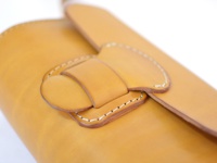 黃色皮革寬扣帶馬鞍包，以縫線裝飾，展現職人手作質感。