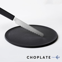 黑色圓形砧板盤上放著一把銀色不鏽鋼鋸齒刀，刀柄為黑色。