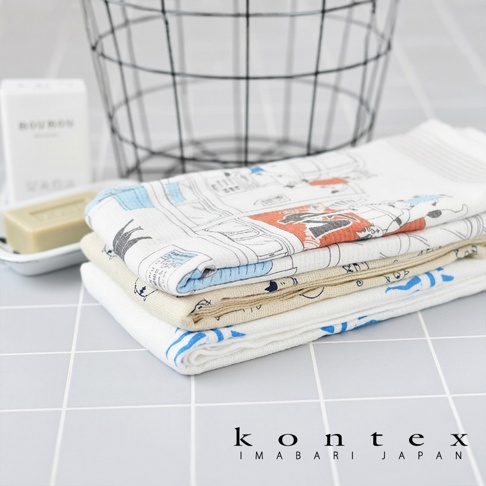 背景為淺灰色格紋磁磚，疊放著三條質感輕薄的 KONTEX Imabari Japan 系列浴巾，最上層的浴巾帶有童趣的漫畫風格圖案，一旁擺放著白色香皂盒與黑色金屬線條置物籃，整體呈現簡潔明亮的日式生活感。