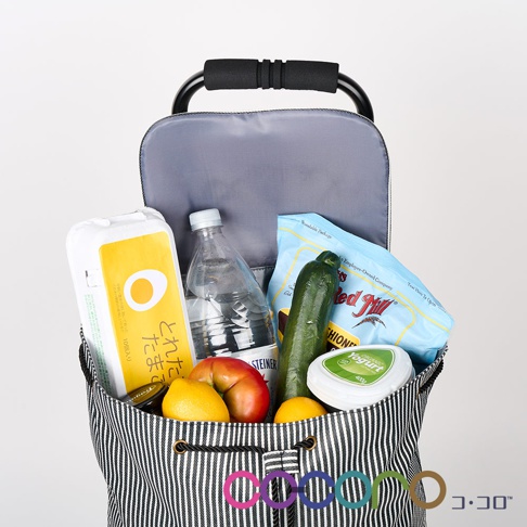 條紋帆布購物車內裝有雞蛋盒、水瓶、小黃瓜、紅蘋果、兩顆檸檬和一盒優格。