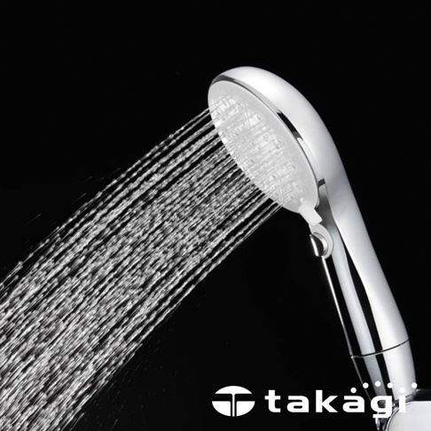 一個銀色金屬質感的 takagi 手持式蓮蓬頭，正噴灑出綿密細緻的強力水柱，整體設計簡潔時尚，側邊設有開關按鈕，在純黑色背景的襯托下呈現出清晰的水流動態感。