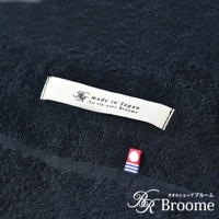 深藍色毛巾被，材質為柔軟的毛圈織物，表面可見「made in Japan」標籤及紅色、藍色條紋裝飾的小標誌。