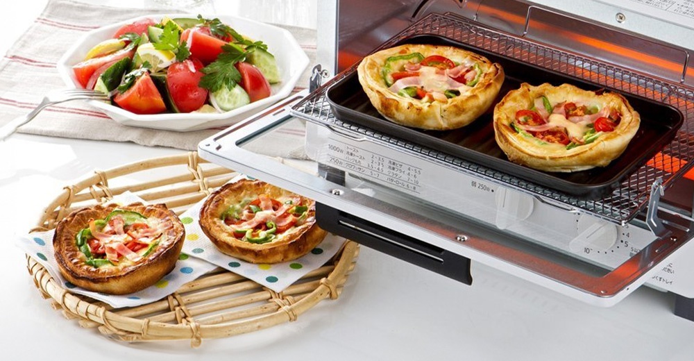烤箱正在烘烤著美味的披薩小點，旁邊擺放著一份新鮮的蔬菜沙拉，展現出豐盛的餐點畫面。