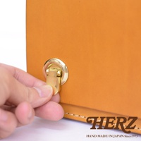 職人手作皮革經典兩用雙扣迷你單肩包，特寫展示標誌性的金色金屬旋轉鎖扣，以及包款的淺棕色皮革材質與細緻縫線。