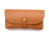 職人手作皮革眼鏡收納盒，採用棕褐色皮革製成，帶有金屬釦帶，邊緣以白色縫線裝飾，設計簡約。