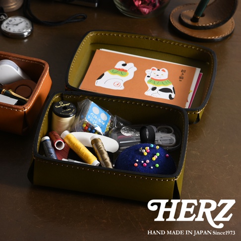 職人手作皮革小物收納盒，橄欖綠色，內含針線、小剪刀、絨布針墊等多樣縫紉小物，另一個橘棕色皮革收納盒內有懷錶及鋼筆。