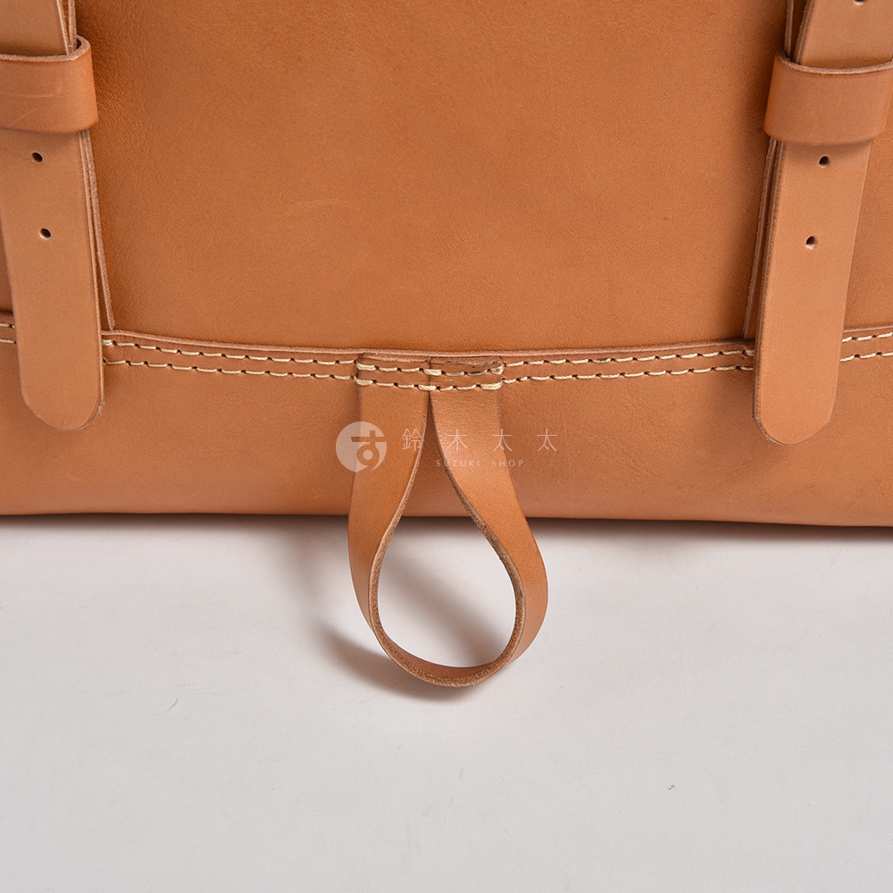 職人手作皮革後背包，棕褐色，展示包包底部提把及側邊皮革縫線細節。