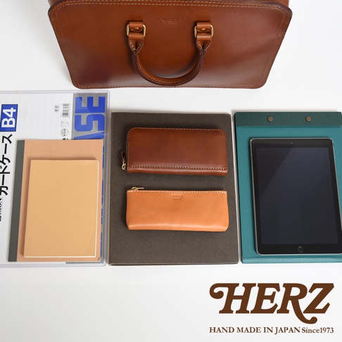 職人手作皮革手提商務公事包 BW-13，淺棕色皮革，搭配兩個同色系皮革長夾與筆記本，以及一個平板電腦，整體呈現簡約質感。