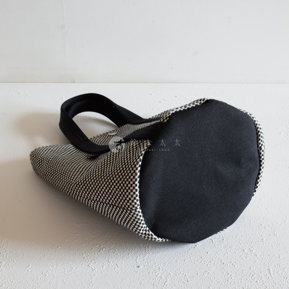 三河木綿刺子織的兩用水桶包，以黑白格紋圖案為主，搭配黑色提把與底部，呈現簡約的日式風格。