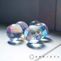 五顆透明的合光稜鏡球，表面有許多切割面，折射出彩虹般的光芒，散落在淺色背景上。