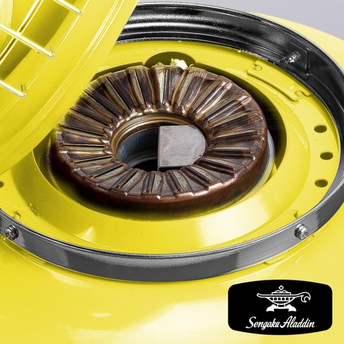 黃色卡式瓦斯暖爐的燃燒器特寫，燃燒器為黃銅色，有放射狀的散熱片，中心有方形金屬塊，暖爐外殼為亮黃色烤漆，邊緣有銀色金屬圈固定。