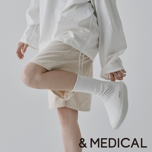 &MEDICAL 品牌白色健身機能鞋，搭配米色短褲和白色長襪，展現簡約休閒風格。