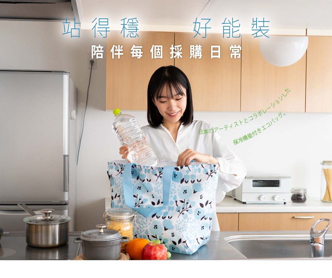 一位年輕女性在廚房流理台前，將一瓶大罐裝飲用水放入藍色花朵圖案的 Prairie Dog 保溫保冷摺疊收納袋中，該收納袋強調站立穩定且具備保冷機能，畫面設計融入日式藝術風格，傳達輕鬆生活的日常採購情境。