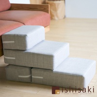 淺灰色織物材質的可折疊寵物樓梯，共三層，堆疊在木質地板上，旁邊是紅色布藝沙發。