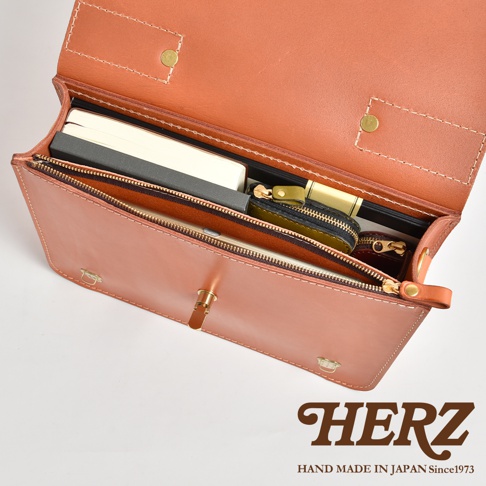 職人手作皮革公事包，採用經典三扣設計，內部隔層可收納筆記本、文件及零錢包，展現皮革溫潤質感與精緻縫線。