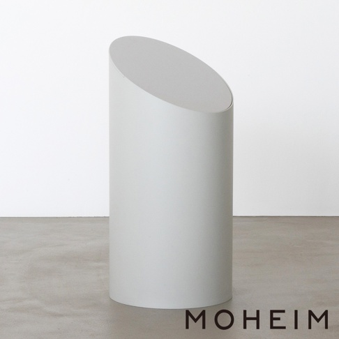 一個灰色的圓柱形垃圾桶，頂部有一個傾斜的開口，側面印有「MOHEIM」品牌標誌。