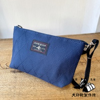 深藍色刺子織隨身斜背包，帶有黑色織帶和金屬掛鉤，包面上方有一個印有「犬印鞄製作所」字樣和圖案的黑色標籤。