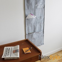 淺灰色布質口袋門簾，帶有五個收納口袋，口袋邊緣及門簾側邊緣有紅色車縫線，上方印有白色文字。