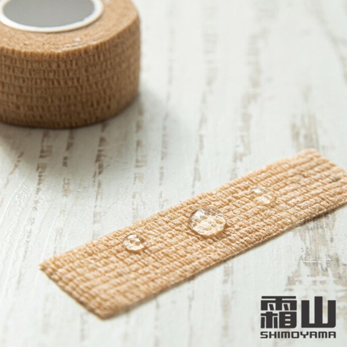 淺褐色纏繞式膠帶，質地呈現編織紋理，表面有水珠。另一捲膠帶置於背景，顯示其材質與紋路。