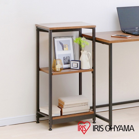 鐵木層架，深棕色木質層板搭配黑色金屬框架，三層窄型設計，上方層板擺放相框、燭台、白色花瓶及方形擺飾，下方層板置有書籍。