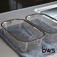 兩個簡約設計的不鏽鋼深型瀝水籃，網狀結構，框架和提把為銀色金屬，其中一個籃子放置在藍灰色布料上。