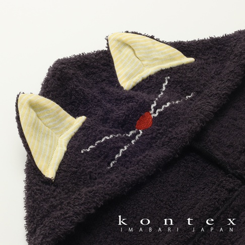 深棕色純棉浴巾，帶有黃白條紋內襯的貓耳朵造型。浴巾上有紅色愛心鼻和白色捲曲鬍鬚的繡線。