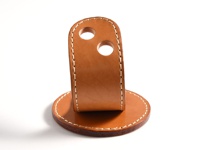 一個由棕色皮革製成，帶有白色縫線的兩用筆架。底部為圓形底座，上方為直立的支架，支架頂部有兩個圓形開孔。