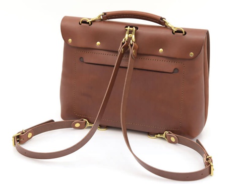 棕色皮革雙扣兩用側背包，帶有可調節的皮革肩帶和金色金屬配件，包身背面有一個外部插袋。