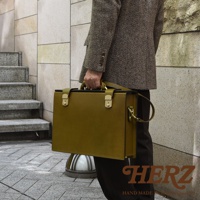 職人手作皮革兩用機師箱，olivine 綠色，配有金色鎖扣和可拆卸肩帶，展現精緻工藝。