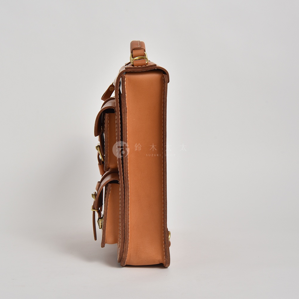 職人手作皮革三口袋三用後背包，淺棕色，光滑皮革材質，帶有兩個前置口袋，以皮帶和金屬釦固定，頂部有提把。