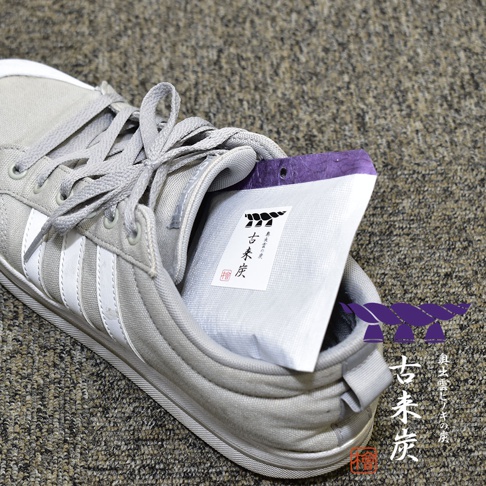 一隻淺灰色運動鞋內放著一個白色包裝的調濕木炭，包裝上有日文標示，並有紫色邊緣。