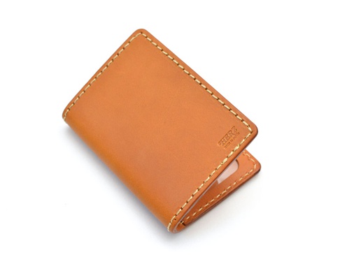 焦糖色皮革雙折票券收納夾，帶有米白色縫線，右下方壓印有「HERZ MADE IN JAPAN」字樣。