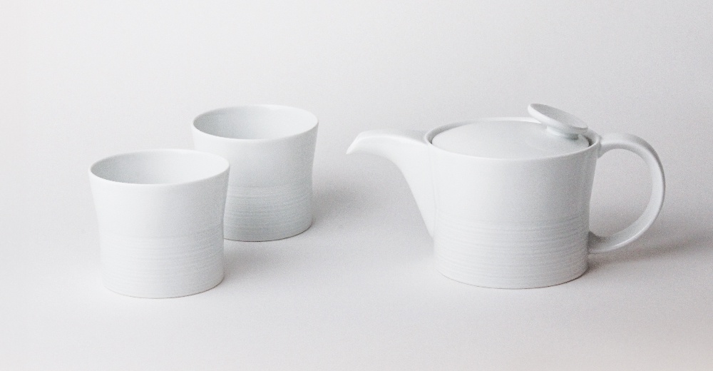 白色陶瓷麻紋飲茶組，包含一個帶有圓形把手和蓋子的茶壺，以及兩個無把手的杯子。