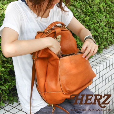 職人手作皮革輕旅行後背包，採用天然棕色皮革，款式簡約，配有金屬扣環與拉鍊，適合日常或短途旅行。